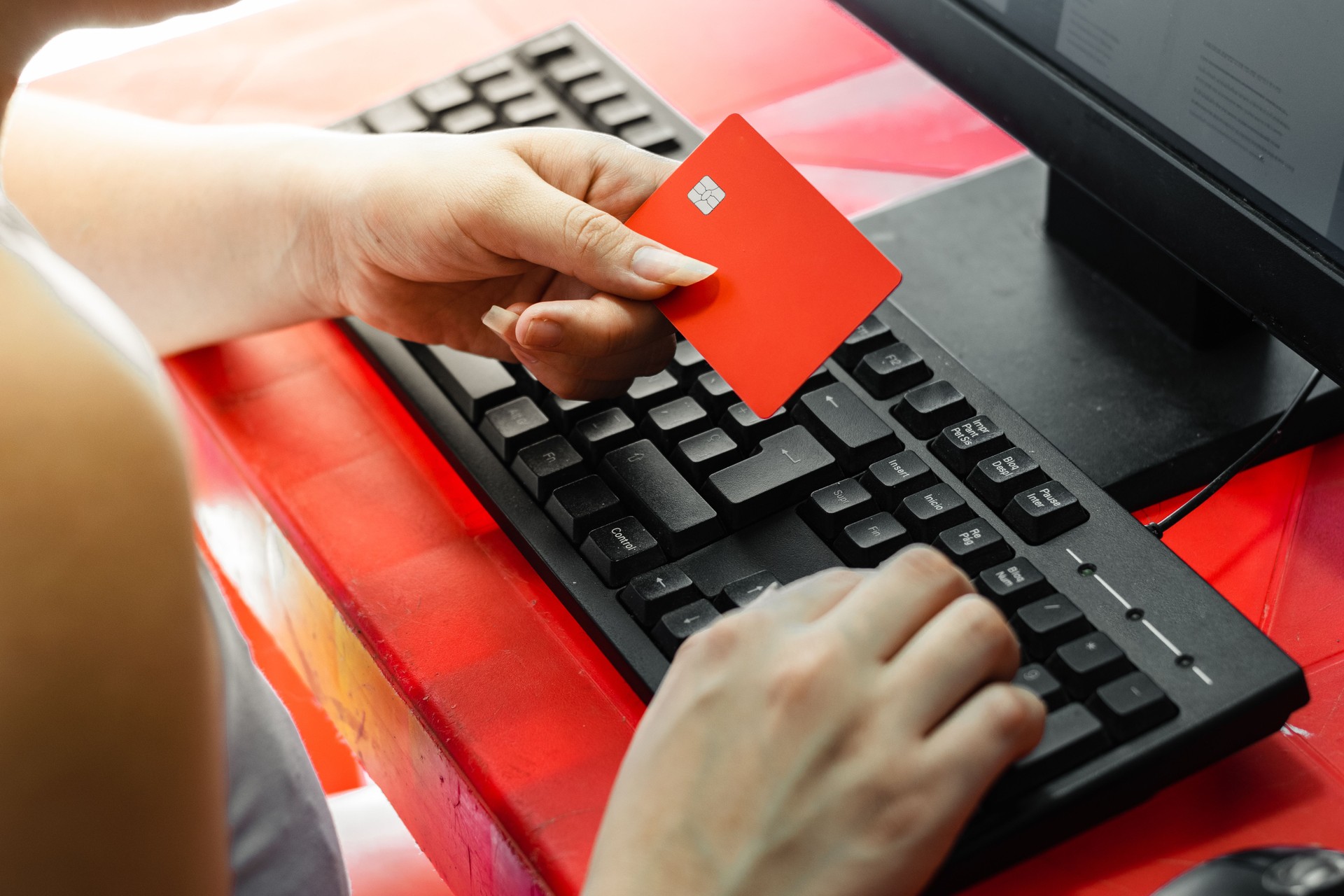Joven latina con tarjeta en mano mientras escribe la contraseña en el teclado de la computadora
